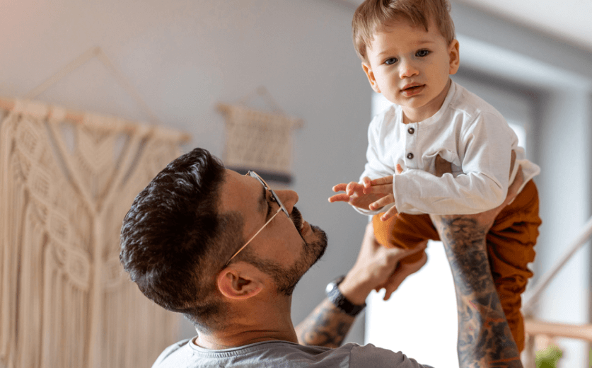 Father wearing glasses holding his young child, symbolizing family vision coverage through VSP Individual Vision Plans.